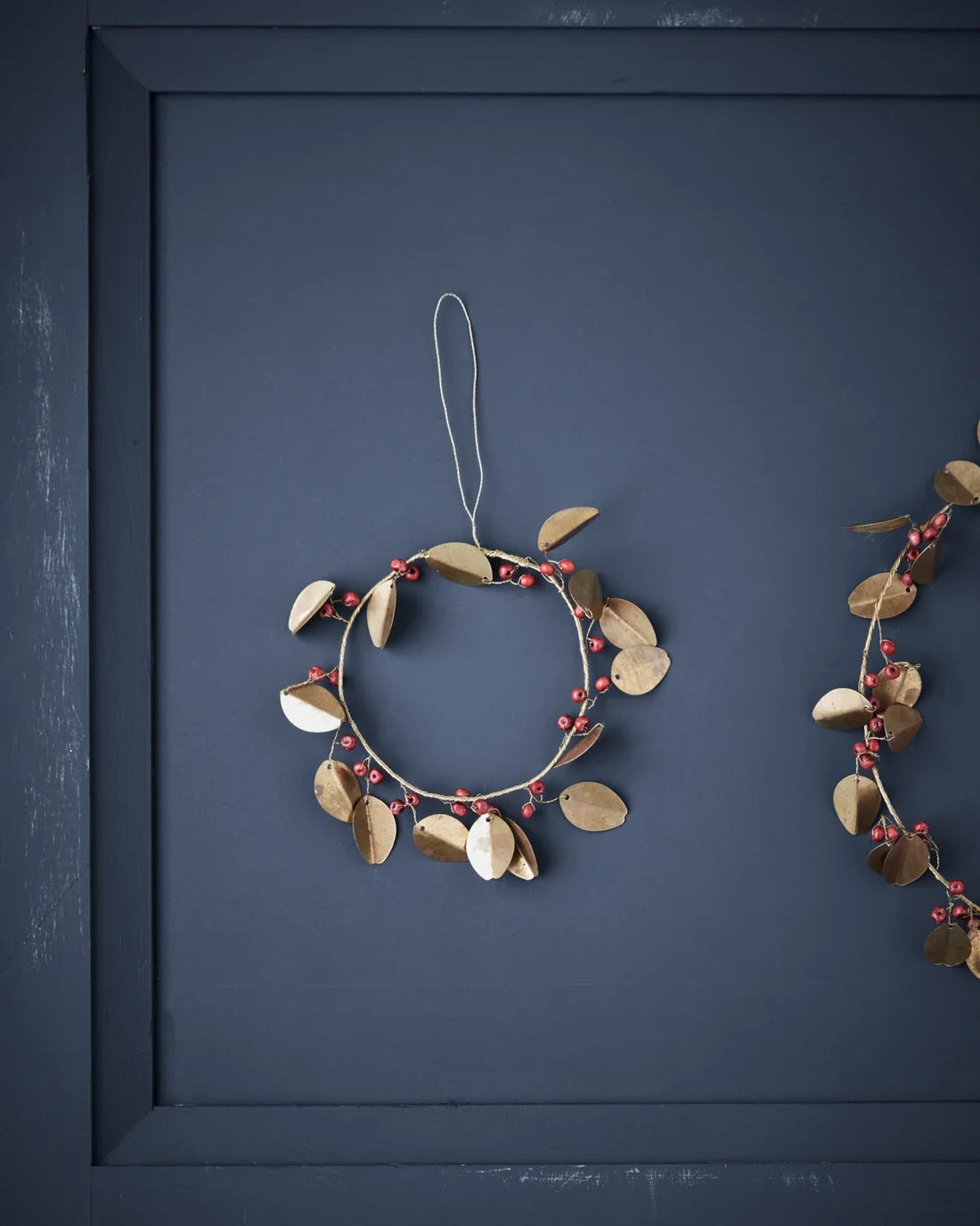 Weihnachtskranz mit goldenen Messingblättern und roten Holzperle