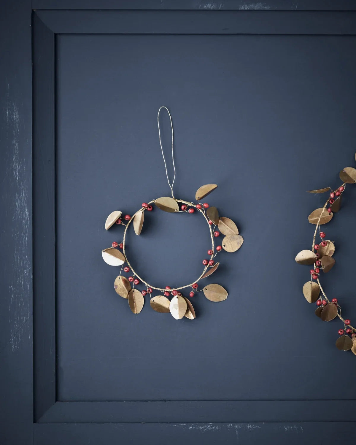 Weihnachtskranz mit goldenen Messingblättern und roten Holzperle